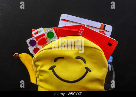Yellow school backpack with accessories on black background Stock Photo