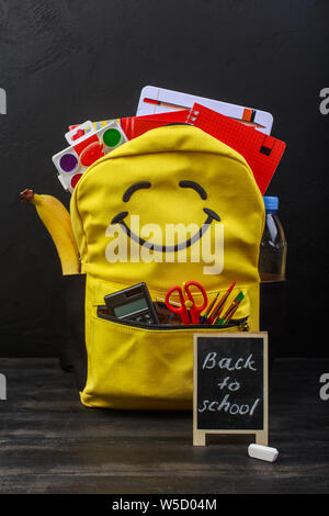 Yellow school backpack with accessories on black background Stock Photo