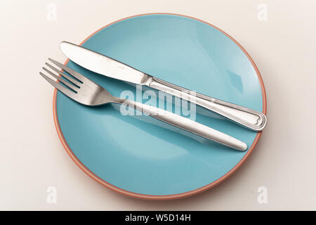Knife and fork on pastel blue plate on white table Stock Photo