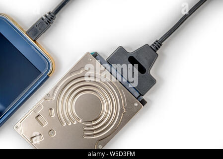 hdd 2.5 hard drive disk connected to smartphone via sata usb cable closeup overhead view Stock Photo