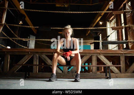 Full length portrait of strong young woman waiting by boxing ring at sports club, copy space Stock Photo