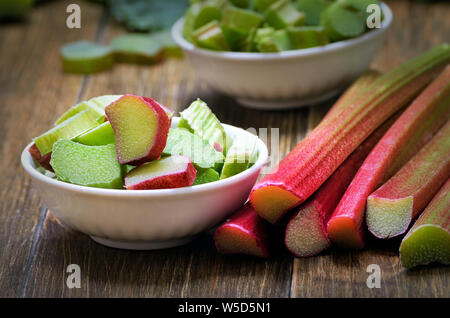 Fresh rhubarb in white bowl on wooden table Stock Photo