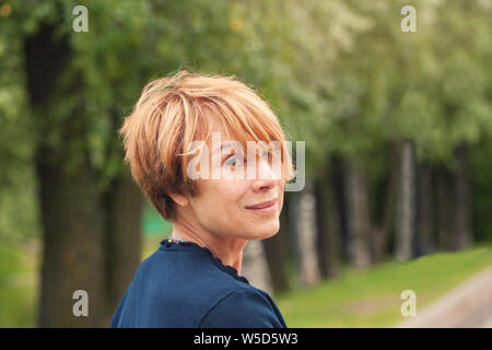 Perfect Mature beauty. Beautiful redhead older woman with trendy layered bob haircut in park Stock Photo