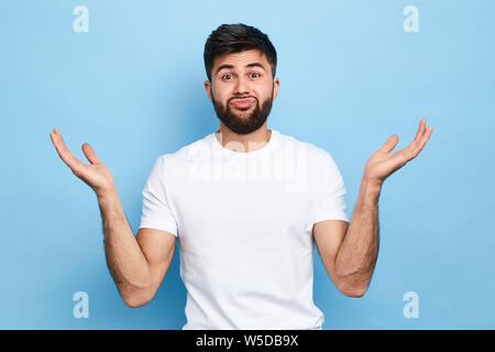 Clueless puzzled handsome guy having hesitation, shrugging his shoulders, Facial expressions. young bearded man cannot solve his problems, close up po Stock Photo