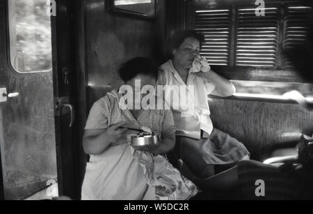 [ 1950s Japan - Japanese Women in Train ] —   Working women returning home on the train after a day’s work in the city, 1958 (Showa 33). One of them is eating a home-made bento. Stock Photo