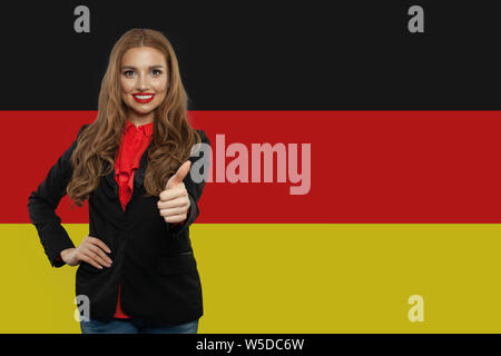 Travel in Germany concept. Pretty woman showing thumb up against the Germany flag background Stock Photo