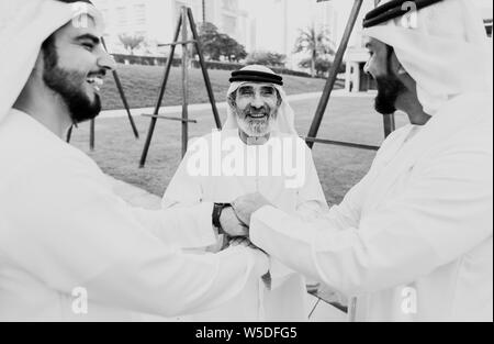 Three business men walking in Dubai wearing traditional emirati clothes Stock Photo
