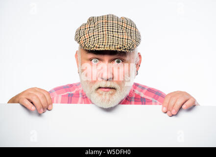Elderly person. Announcement concept. Event announcement. Pensioner grandfather in vintage hat poster information copy space. Senior bearded emotional man peek out of banner place announcement. Stock Photo