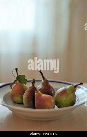 ripe pears in a deep plate on the table, summer food Stock Photo
