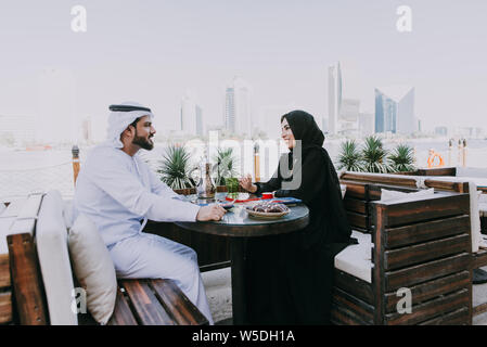 Happy couple spending time in Dubai. man and woman wearing traditional clothes having a conversation in a cafe Stock Photo