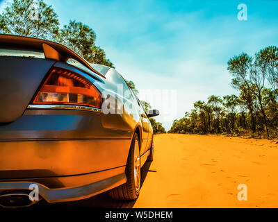 Vivid photo of a gleaming silver car traveling down a dusty outback road in Northern Australia. Stock Photo