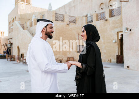 Happy couple spending time in Dubai. man and woman wearing traditional clothes making shopping in the old city Stock Photo