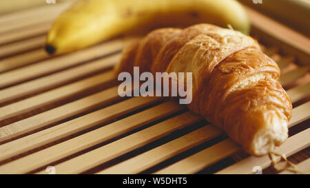 Banana and croissant on rustic wooden background. Selective focus, horizontal. Stock Photo