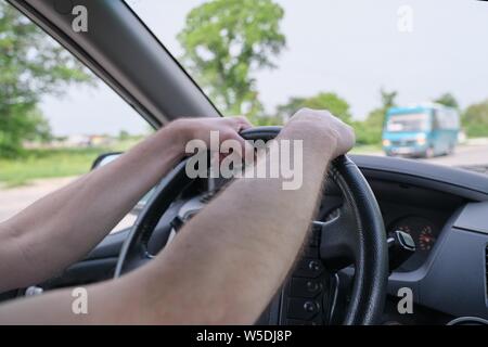 Drivers men hands on steering wheel, day time Stock Photo