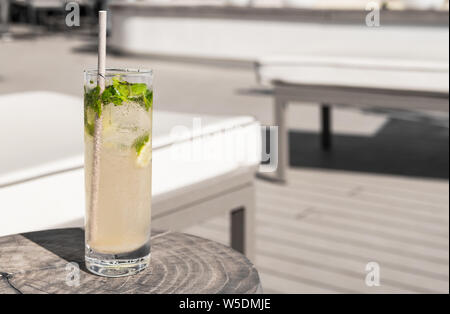 Virgin Mojito with paper straw on a wooden table near a luxury deck chair. Summer vacation drink. Stock Photo