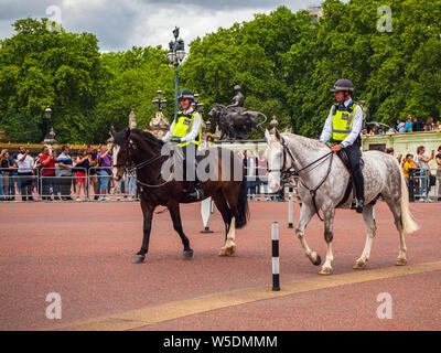 Mounted police on horseback patrolling outside Buckingham palace in England surrounded by crowds of tourists Stock Photo