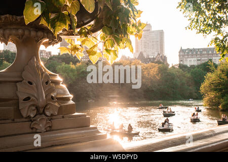 Summer in Central Park New York City seen from historic Bow Bridge with unknown people in row boats in the lake. Stock Photo