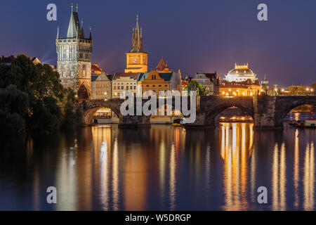 Panoramic view over the river Vltava to Charles Bridge at night in Prague. Old Town tower and historic stone bridge with lighting between the old town
