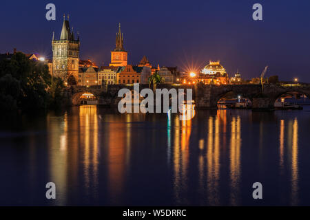 Prague with Charles Bridge at night. Panoramic view over the Vltava. Old Town tower and historic stone bridge with lighting between the old town