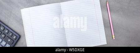 Flat lay, top view, notebook, pencil, calculator on a gray textured background. Rays of light from the side Stock Photo