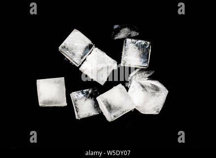 Cubes of Ice isolated on black Background, pieces of crushed ice with Snow on Top Stock Photo