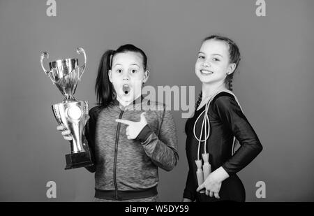 Deserved award. Girls athletic kids celebrate victory. Athletic girls with golden goblet. Win championship. Our team first place. Children gymnasts athletic kids happy champions. Sport achievement. Stock Photo