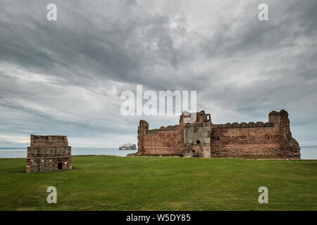 The 14th century fortress of Tantallon castle in East Lothian in Scotland with Bass Rock in the distance and an ancient pigeon house in the foreground Stock Photo