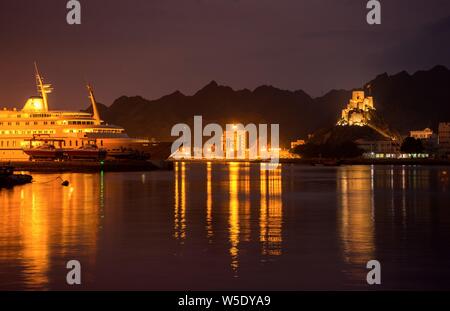 Beautiful view of the Muscat port of Oman with a lighted ship and background fort at night time. Stock Photo