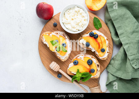 Peach And Ricotta Bruschetta On Wooden Serving Board. Healthy Summer Appetizer Or Snack Stock Photo