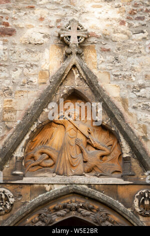 Saint Michael defeating the Dragon Satan, Christian stone carving on the side of Llandaff Cathedral, Cardiff Wales Stock Photo