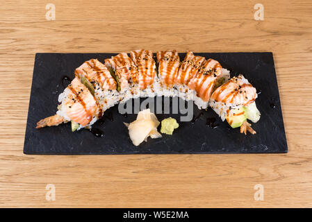 Special Uramaki, rice roll stuffed with shrimp tempura, green salad, avocado, covered with grilled salmon, seasoned with black and white sesame, tamar Stock Photo