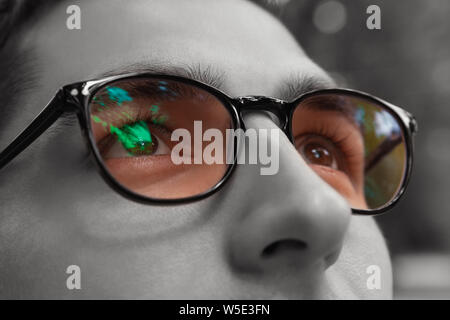 Young man gets colorful bright sight wearing glasses. Eyewear to improve vision. Black and white. Close up of eyes Stock Photo