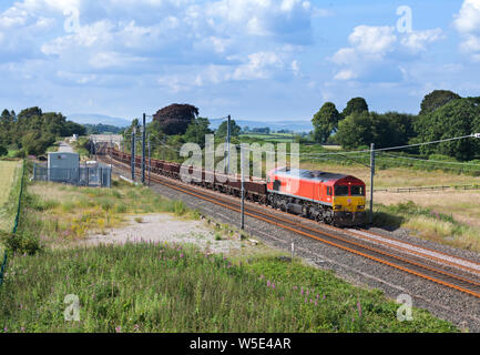 DB Cargo class 66 locomotive on the west coast mainline in Cumbria with a 'departmental' freight train carrying materials for Network Rail Stock Photo