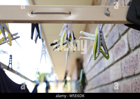 Different coloured washing pegs on an outdoor washing drying line rack attached to the side of the house. Stock Photo