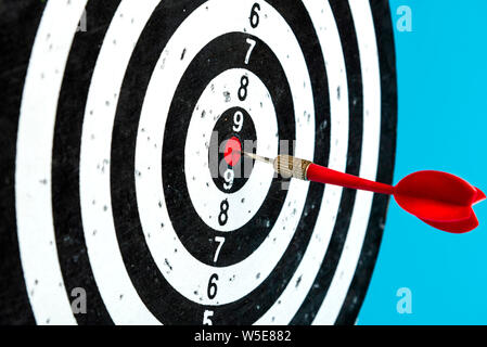 Aim with arrow in the center. Target on a blue background with a red dart. Stock Photo