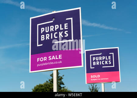 Two Purple Bricks signs side-by-side. One indicating a property 'for sale' and the other 'sold' (Editorial use only). Stock Photo