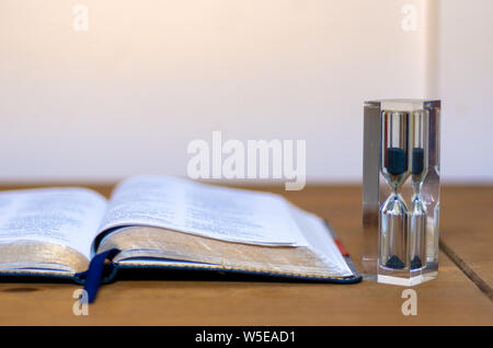 An open bible by an hourglass. Can illustrate themes of time. Stock Photo
