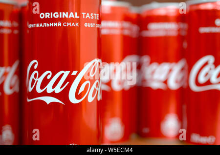 KHARKIV, UKRAINE - JULY 25, 2019: Coca-Cola logo printed on aluminium cans and placed on shopping mall table. Coca-Cola is a carbonated soft drink sol Stock Photo