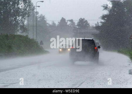 Cars driving too fast in heavy rain on wet roads with poor visibility ...