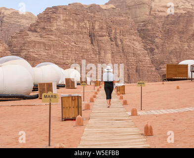 A woman walks down the pathway to her bubble tent in Wadi Rum, Jordan. Stock Photo