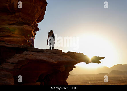 A woman walking onto a ledge in Wadi Rum at sunset. Stock Photo