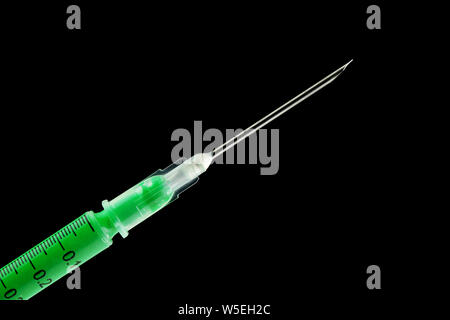 Syringe filled with green drug and dripping from the needle - isolated on black Stock Photo