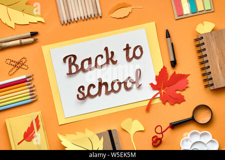 Back to school cut-out text, flat lay on dark texture background with stationary and Autumn leaves Stock Photo