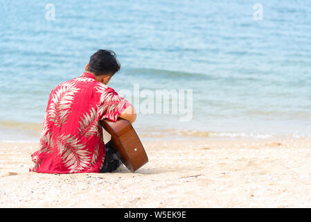 Man hand playing guitar on the beach. Acoustic musician playing  classic guitar. Musical Concept. Stock Photo