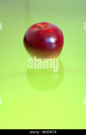 Red apple over a green reflective surface. Well suited for a concept background. Stock Photo