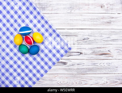 Colorful chicken easter eggs on checkered motley fabric and white wooden background, copy space, texture Stock Photo