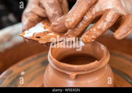 Hands of the potter. The potter makes pottery dishes on potter's wheel. The sculptor in workshop makes clay product closeup Stock Photo
