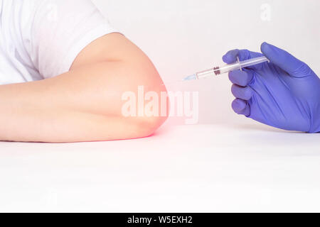 A doctor makes an injection into the elbow joint of a woman who has pain and inflammation in the elbow joint, a concept of modern medicine, plasma the Stock Photo