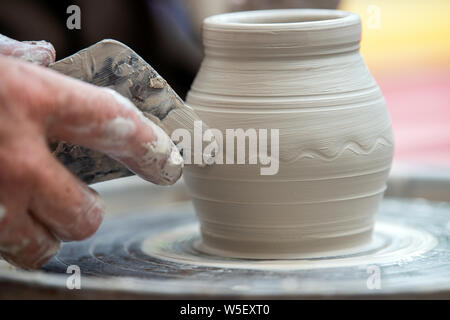 Hands of the potter. The potter makes pottery dishes on potter's wheel. The sculptor in workshop makes clay product closeup Stock Photo