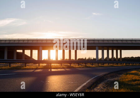 Transport bridge at a road junction for unloading traffic on the road, evening, sunset, copy space, interchange Stock Photo
